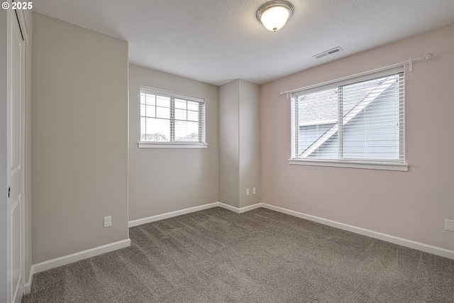 carpeted empty room with baseboards, visible vents, and a textured ceiling