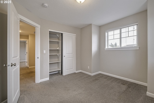 unfurnished bedroom with a closet, carpet flooring, a textured ceiling, and baseboards