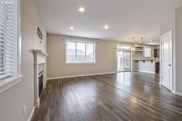 unfurnished living room featuring recessed lighting, dark wood-style flooring, a tiled fireplace, and baseboards