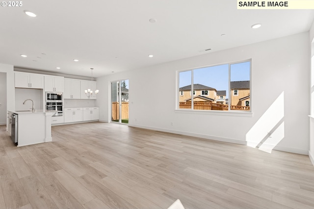 2149 NE Singer Ln, Estacada, OR 97023 - unfurnished living room with a chandelier, recessed lighting, light wood-style floors, and a sink