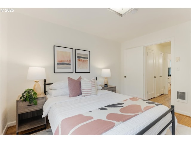 bedroom with visible vents, light wood-style flooring, and baseboards