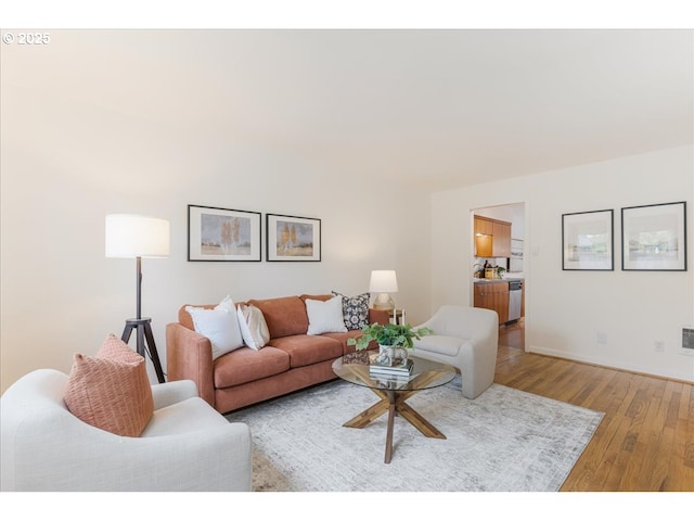 living area with baseboards, light wood-style flooring, and visible vents