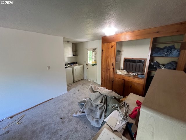 carpeted living area with a textured ceiling and washer and dryer