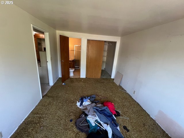 unfurnished bedroom with carpet floors, connected bathroom, and a closet