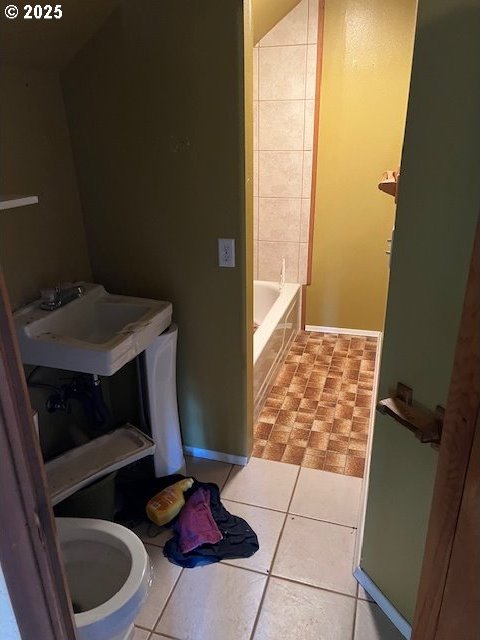 bathroom featuring toilet, baseboards, a sink, and tile patterned flooring