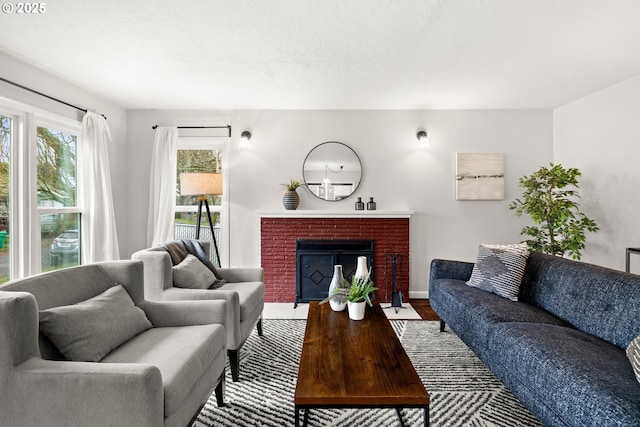 living area featuring a brick fireplace, wood finished floors, and a textured ceiling