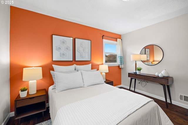 bedroom with visible vents, wood finished floors, and baseboards