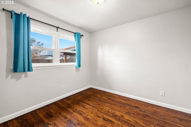 unfurnished room featuring dark wood-style floors, a textured ceiling, and baseboards