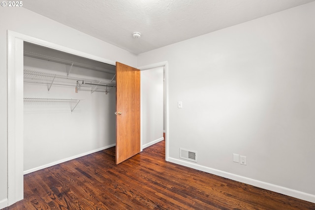 unfurnished bedroom with a closet, visible vents, baseboards, and wood finished floors