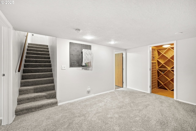 finished below grade area with baseboards, carpet floors, a textured ceiling, and stairs