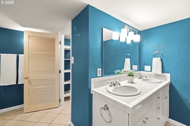 full bathroom with a sink, baseboards, a textured ceiling, and tile patterned flooring