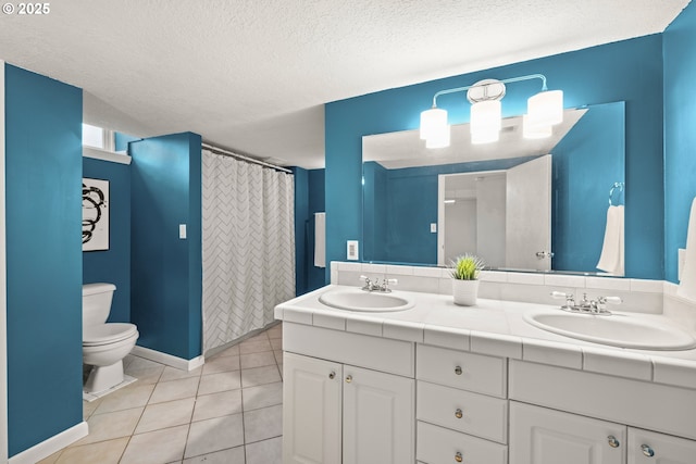 bathroom with toilet, double vanity, tile patterned floors, a textured ceiling, and a sink