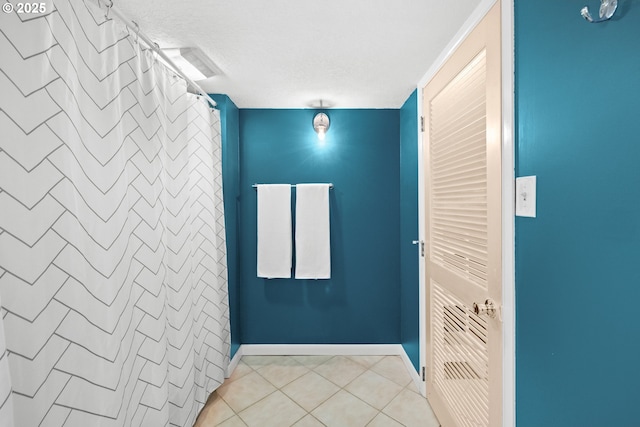 interior space with tile patterned floors, baseboards, and a textured ceiling