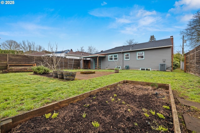 rear view of house with a lawn, a vegetable garden, a fenced backyard, and a chimney