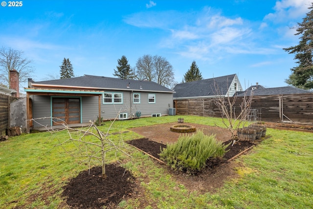 back of house featuring a lawn, a fenced backyard, and an outdoor fire pit