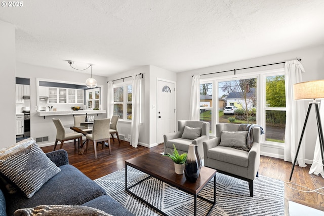 living area with visible vents, a textured ceiling, and wood finished floors