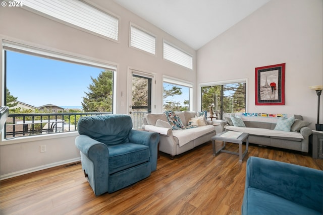 living room featuring visible vents, high vaulted ceiling, baseboards, and wood finished floors