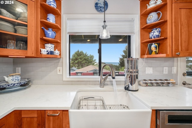 kitchen with brown cabinetry, a sink, and open shelves