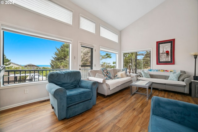 living room with plenty of natural light, wood finished floors, baseboards, and high vaulted ceiling