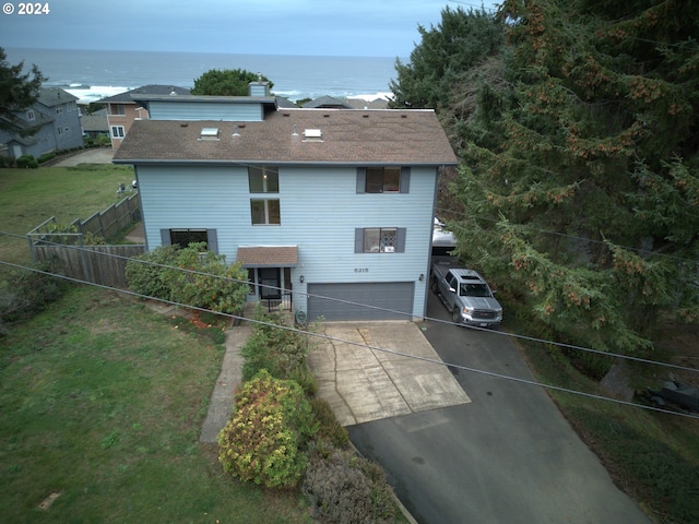 exterior space with a water view, fence, concrete driveway, a front yard, and a garage