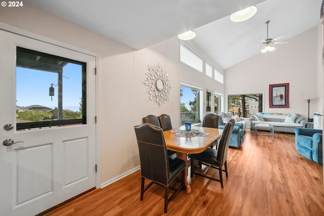 dining area featuring ceiling fan, baseboards, light wood-type flooring, and high vaulted ceiling