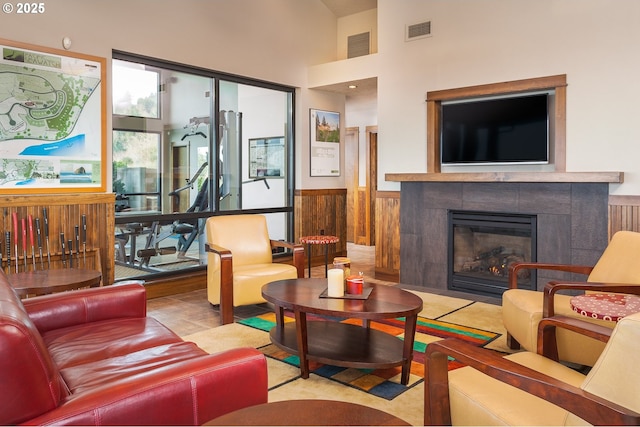 7850 Brooten Mountain Loop, Pacific City, OR 97135 - living room with a wainscoted wall, a tiled fireplace, wooden walls, and a towering ceiling