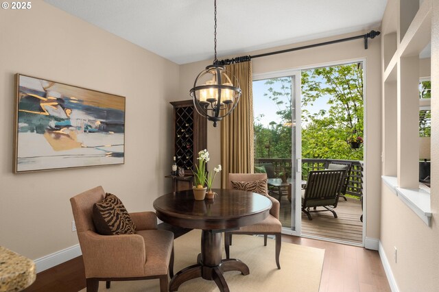 dining area with dark wood-style flooring, baseboards, and an inviting chandelier