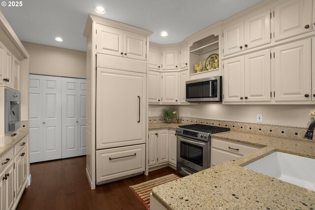 kitchen featuring appliances with stainless steel finishes, a sink, a peninsula, an inviting chandelier, and recessed lighting