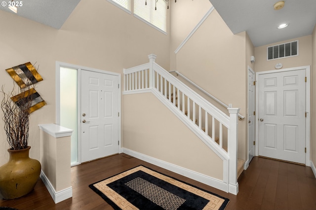 foyer with stairs, dark wood-style flooring, baseboards, and visible vents