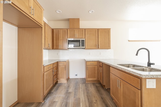 kitchen featuring light stone counters, wood-type flooring, sink, and tasteful backsplash