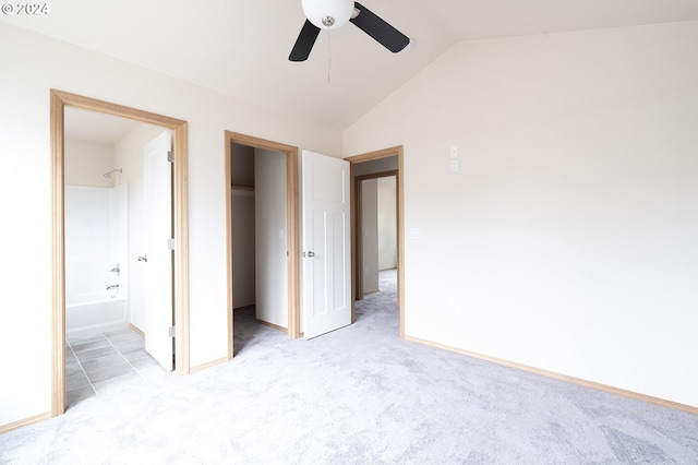 unfurnished bedroom featuring ensuite bathroom, ceiling fan, a spacious closet, a closet, and lofted ceiling