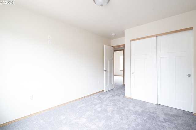 unfurnished bedroom featuring light colored carpet and a closet