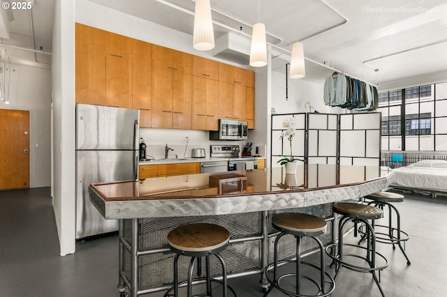 1314 NW Irving St Unit 510, Portland, OR 97209 - kitchen featuring appliances with stainless steel finishes, a sink, concrete flooring, and a breakfast bar area