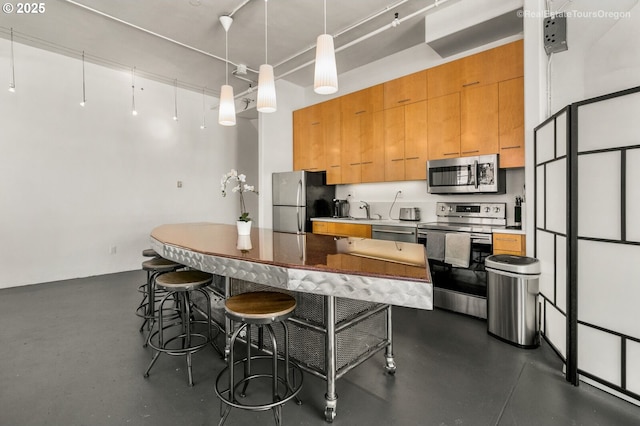 1314 NW Irving St Unit 510, Portland, OR 97209 - kitchen with appliances with stainless steel finishes, a sink, a breakfast bar area, decorative light fixtures, and brown cabinets