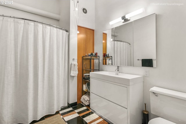 1314 NW Irving St Unit 510, Portland, OR 97209 - bathroom with vanity, toilet, inlaid floor details, and curtained shower
