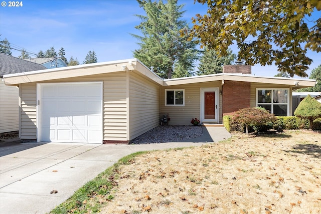 ranch-style house featuring driveway, a chimney, and an attached garage