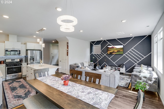 dining space featuring an accent wall, visible vents, recessed lighting, a chandelier, and wood finished floors