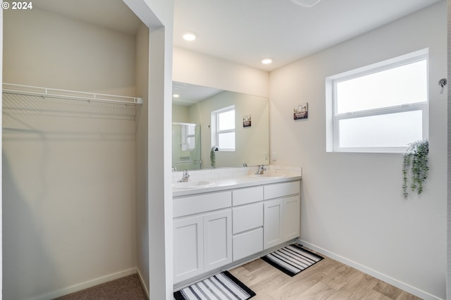 full bath featuring a spacious closet, double vanity, a sink, and a stall shower
