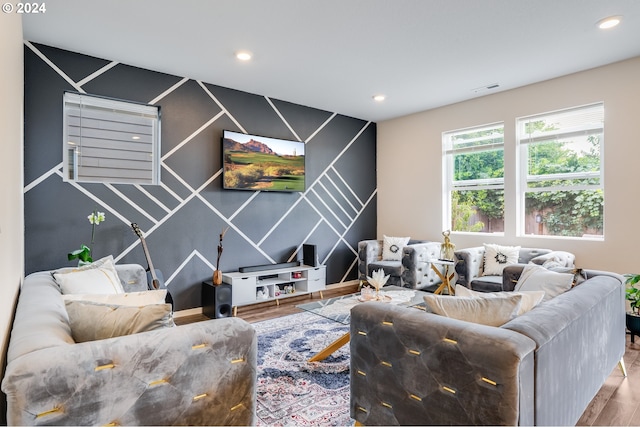 living area with recessed lighting, an accent wall, visible vents, and wood finished floors