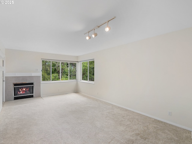 unfurnished living room with a tiled fireplace, light carpet, and track lighting