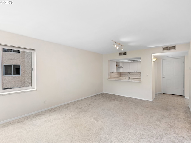 unfurnished living room with light carpet and rail lighting