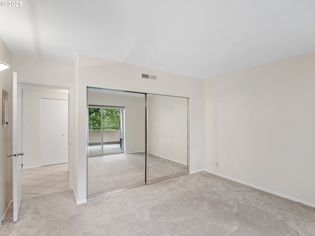 unfurnished bedroom featuring light carpet and a closet