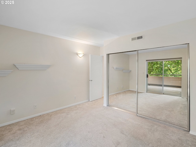 unfurnished bedroom featuring access to outside, light colored carpet, and a closet