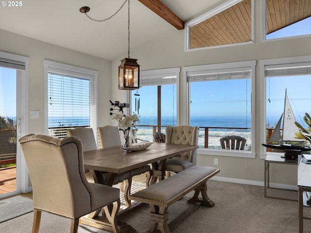 dining area with carpet flooring, plenty of natural light, vaulted ceiling with beams, and a water view