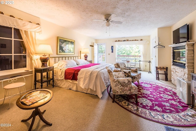 2165 NE E Devils Lake Rd, Otis, OR 97368 - carpeted bedroom featuring access to outside, a textured ceiling, a stone fireplace, and a ceiling fan