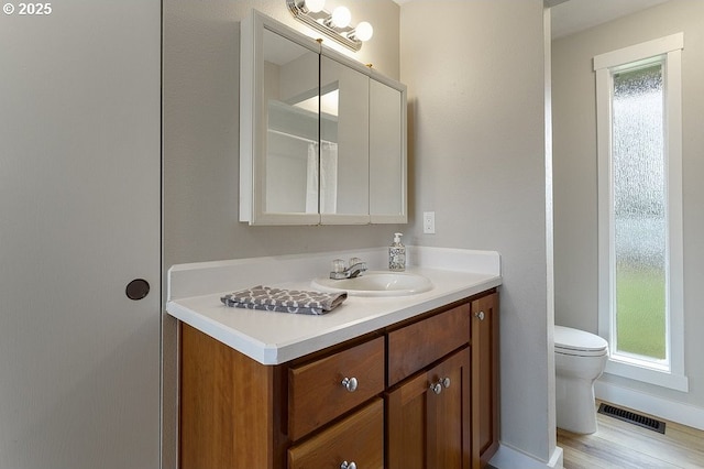 bathroom with toilet, vanity, and wood finished floors