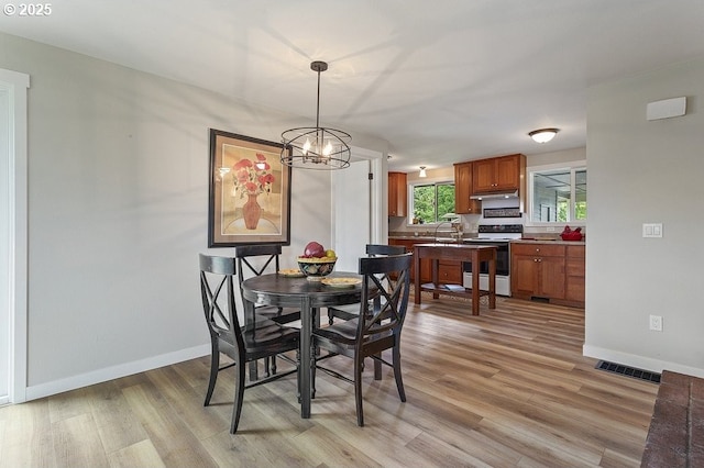 dining area featuring light wood-style floors, a chandelier, and baseboards