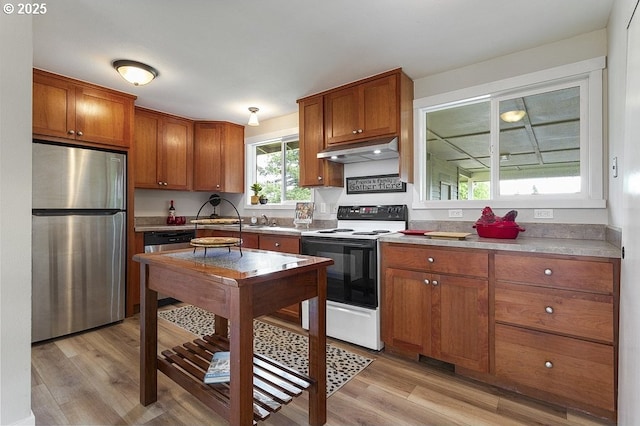 kitchen featuring freestanding refrigerator, range with electric cooktop, under cabinet range hood, and brown cabinets