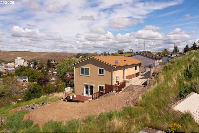 rear view of house featuring a deck, french doors, and stucco siding