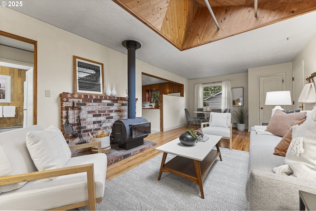 living area with a textured ceiling, a wood stove, baseboards, and wood finished floors